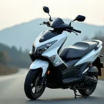 Yamaha XMAX 125 blanc garé sur une route asphaltée en montagne, vue trois-quarts avant mettant en valeur le carénage et le tableau de bord numérique